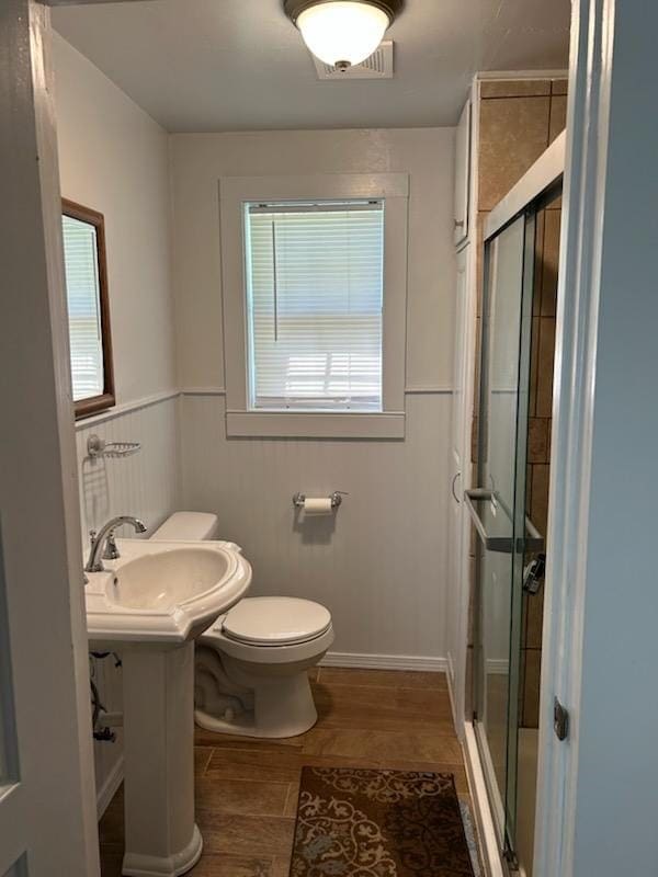 bathroom featuring toilet, a shower stall, and a healthy amount of sunlight