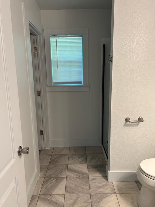 bathroom with toilet, baseboards, and marble finish floor