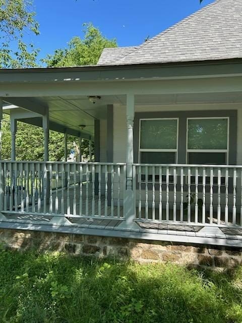 back of property with covered porch and roof with shingles