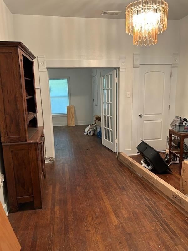 interior space with dark wood finished floors, a chandelier, baseboards, and visible vents