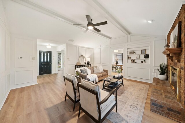 living area with lofted ceiling with beams, a fireplace, a decorative wall, a ceiling fan, and visible vents