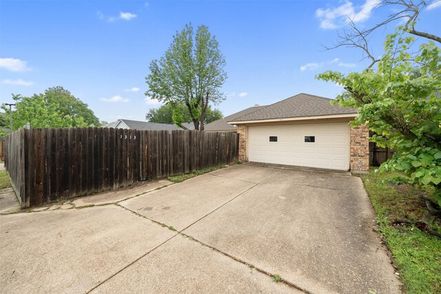 view of side of home with brick siding, a garage, and fence