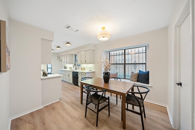 dining space with visible vents, light wood-style floors, and baseboards