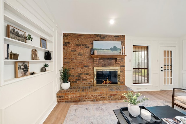 living area featuring built in shelves, wood finished floors, and a fireplace