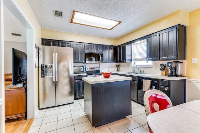 kitchen featuring a sink, light countertops, stainless steel appliances, a kitchen island, and visible vents
