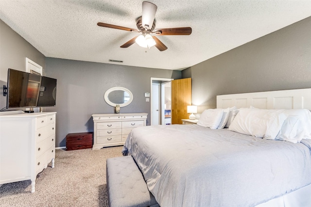 bedroom featuring a textured ceiling, visible vents, light carpet, and ceiling fan
