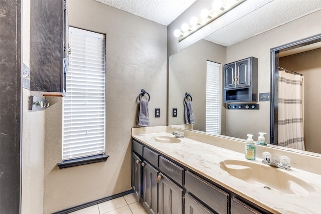 full bathroom with tile patterned flooring, a sink, a textured ceiling, and double vanity