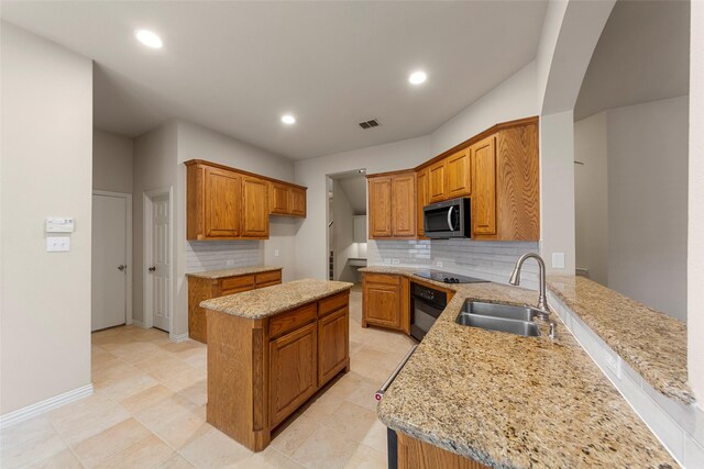 kitchen featuring a sink, brown cabinetry, black appliances, and backsplash