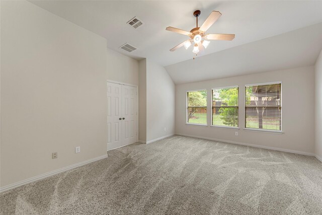 unfurnished room with baseboards, light carpet, vaulted ceiling, and visible vents