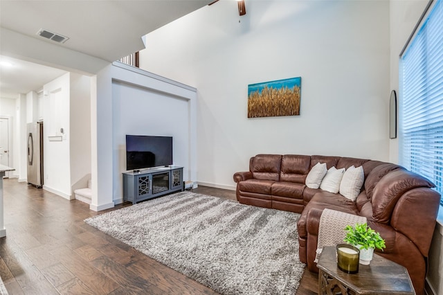 living room with dark wood-style flooring, stairs, a ceiling fan, baseboards, and visible vents