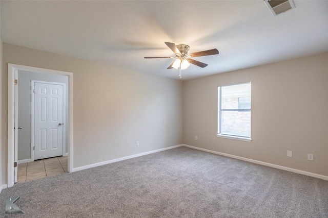 spare room with ceiling fan, light colored carpet, baseboards, and visible vents