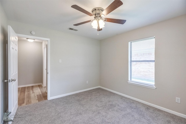 spare room with carpet floors, baseboards, a ceiling fan, and visible vents