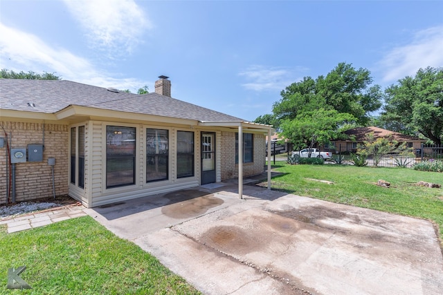 back of property featuring a chimney, a lawn, a patio area, brick siding, and fence