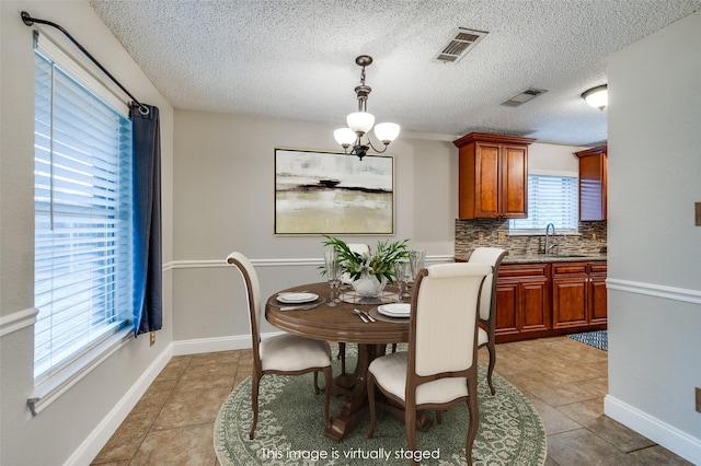 2909 Chisholm Trl, Corinth, TX 76210 - dining area with light tile patterned floors, a chandelier, a textured ceiling, and baseboards