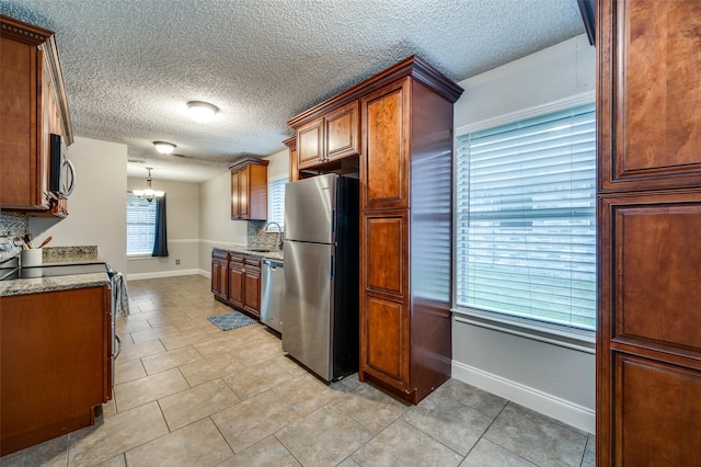 2909 Chisholm Trl, Corinth, TX 76210 - kitchen featuring stainless steel appliances, a sink, a chandelier, baseboards, and a textured ceiling