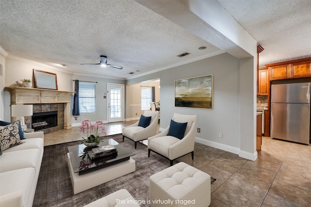 2909 Chisholm Trl, Corinth, TX 76210 - living area with a textured ceiling, ornamental molding, a tiled fireplace, ceiling fan, and baseboards