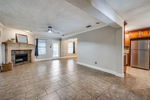 2909 Chisholm Trl, Corinth, TX 76210 - unfurnished living room with a textured ceiling, ornamental molding, ceiling fan, a fireplace, and light tile patterned floors