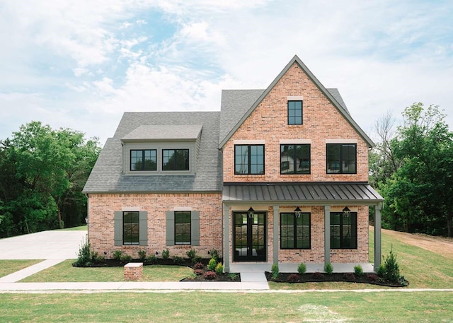 view of front of property featuring brick siding, a shingled roof, covered porch, and a front yard