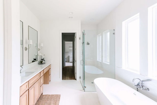 bathroom featuring a shower stall, a soaking tub, and vanity