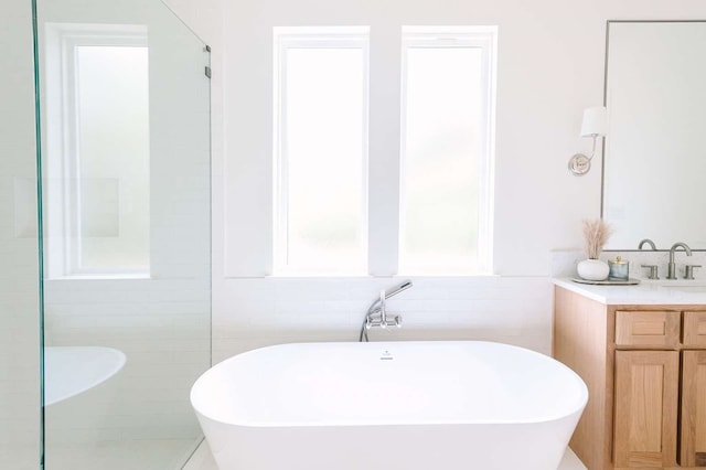 bathroom with a freestanding bath, tile walls, walk in shower, and vanity