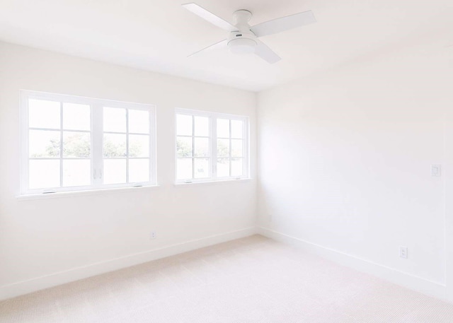 spare room featuring baseboards, a ceiling fan, and light colored carpet