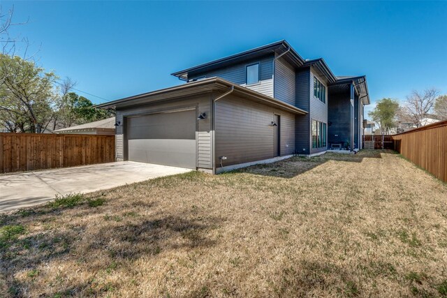exterior space featuring a garage, fence, a lawn, and driveway