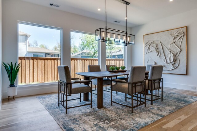 dining space with an inviting chandelier, baseboards, wood finished floors, and visible vents