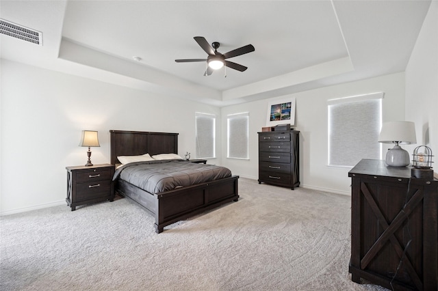 bedroom featuring visible vents, light carpet, baseboards, ceiling fan, and a raised ceiling