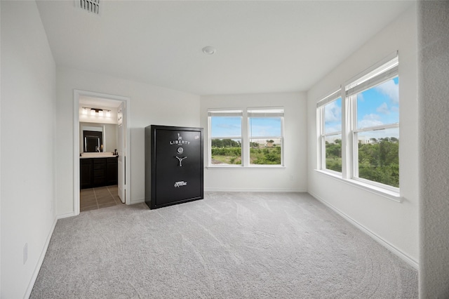 unfurnished bedroom with connected bathroom, baseboards, visible vents, and light carpet
