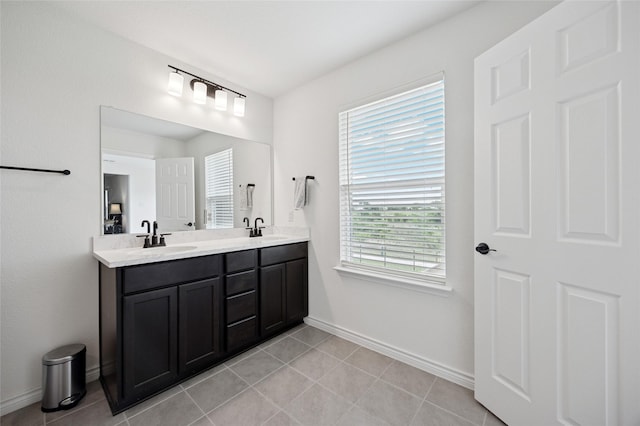 bathroom featuring a sink, baseboards, tile patterned floors, and double vanity