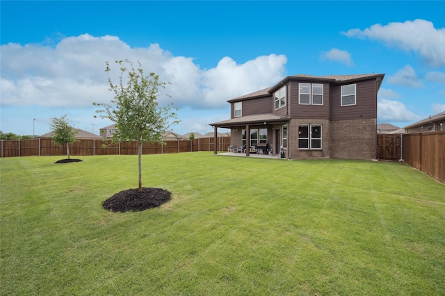 back of house with a lawn, brick siding, a fenced backyard, and a patio area