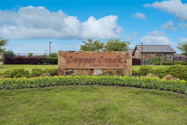 community / neighborhood sign featuring fence and a lawn
