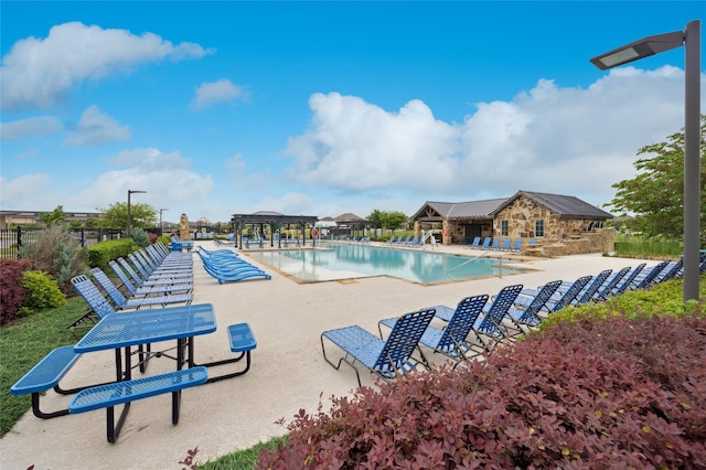 community pool with fence, a gazebo, and a patio area
