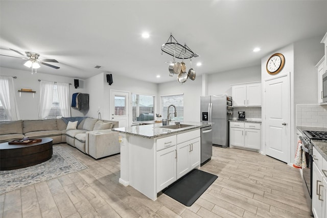 8557 Big Apple Dr, Fort Worth, TX 76179 - kitchen featuring a sink, stainless steel appliances, a kitchen island with sink, backsplash, and light wood-style floors
