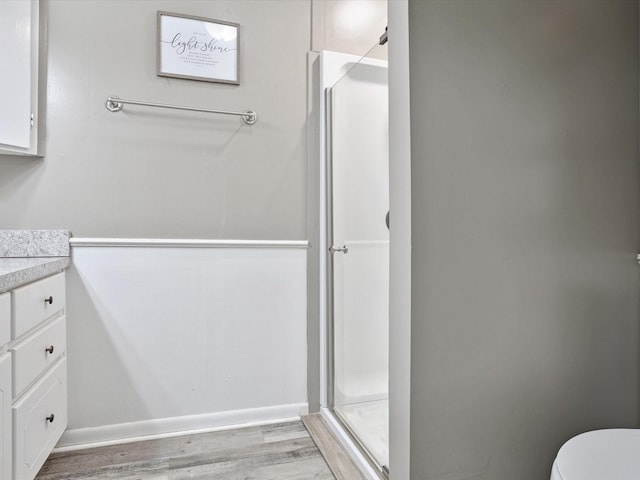 full bath featuring vanity, toilet, baseboards, a shower stall, and wood finished floors