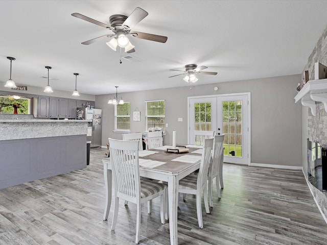 dining space with french doors, light wood finished floors, and ceiling fan with notable chandelier