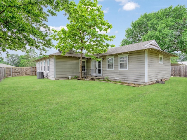 back of house with a shingled roof, a fenced backyard, central AC unit, french doors, and a lawn