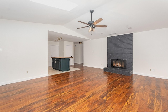 unfurnished living room featuring ceiling fan, a fireplace, wood finished floors, lofted ceiling, and visible vents