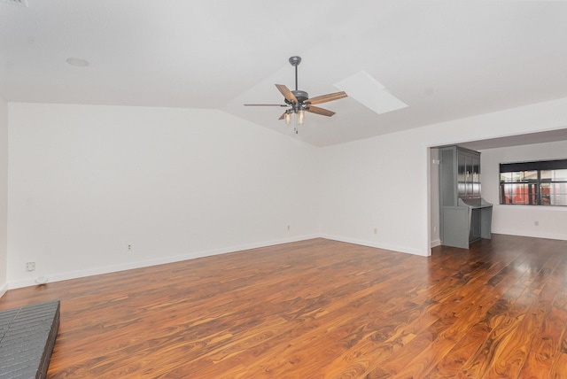 unfurnished living room featuring vaulted ceiling with skylight, baseboards, a ceiling fan, and dark wood-type flooring