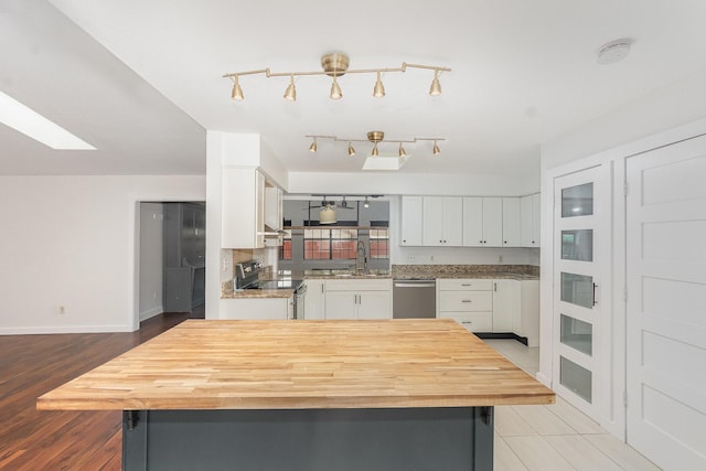 kitchen with white cabinets, appliances with stainless steel finishes, wooden counters, baseboards, and a kitchen island
