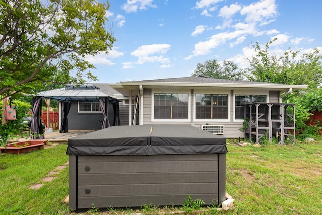 back of property featuring a hot tub, a gazebo, and a yard