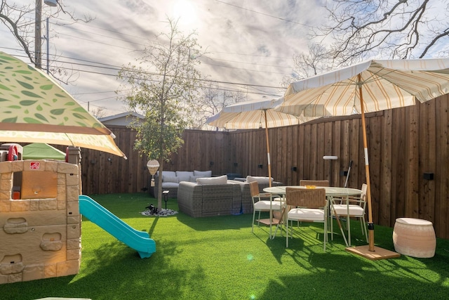 view of yard featuring outdoor dining area, a fenced backyard, and a playground