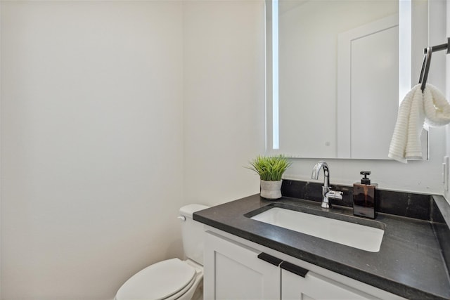 half bath featuring vanity and toilet