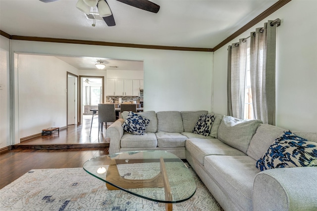 living area with crown molding, baseboards, a ceiling fan, and wood finished floors