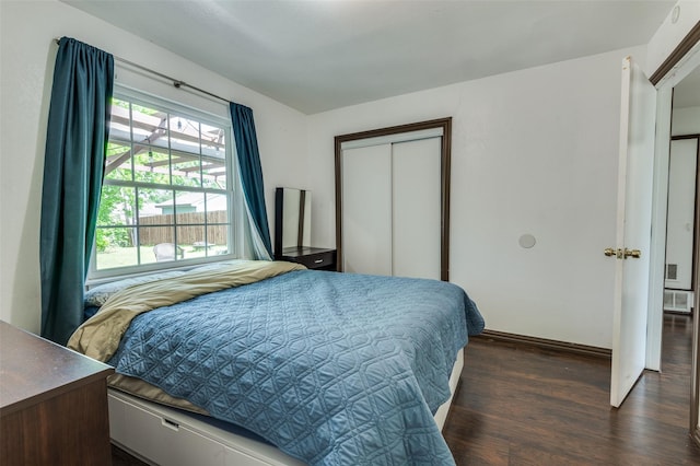 bedroom with baseboards, dark wood-style floors, and a closet