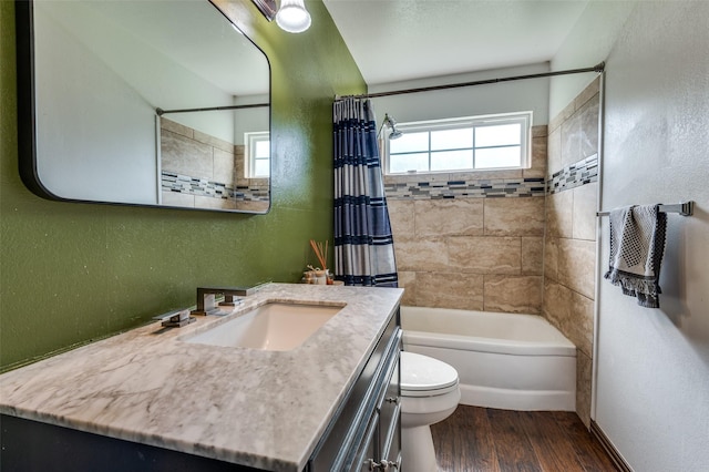 bathroom featuring a textured wall, vanity, shower / tub combo with curtain, toilet, and wood finished floors