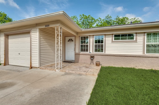 view of exterior entry with an attached garage and concrete driveway