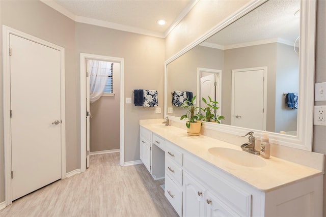 bathroom with double vanity, a sink, crown molding, and wood finished floors