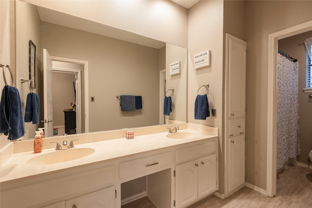 full bath featuring double vanity, a sink, and wood finished floors