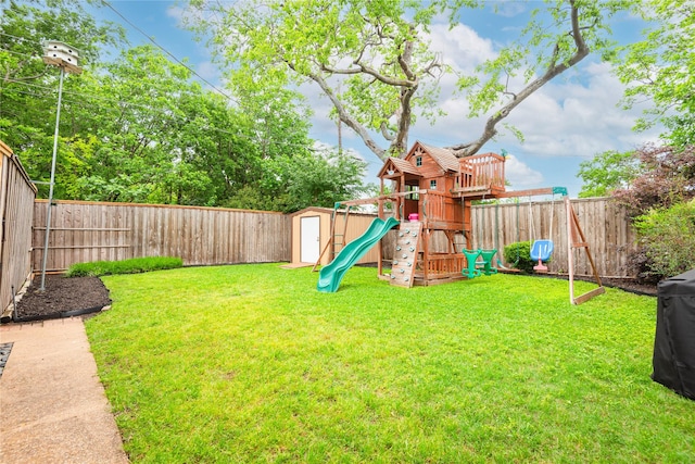 view of playground with a yard, an outdoor structure, a fenced backyard, and a storage unit